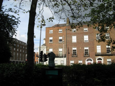 while the other pillar has a bronze male torso.In the background, Wilde´s old family home number 1 Merrion Square.